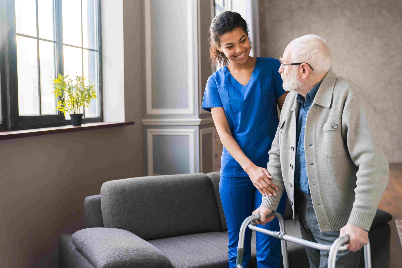 A home carer helping an older client walk safely with a frame